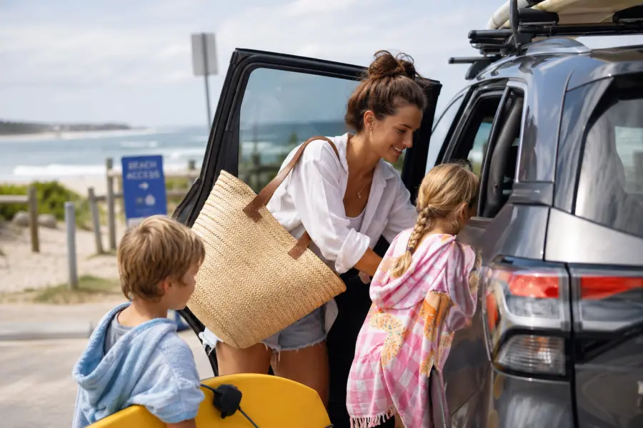 Au Pair chargeant la voiture avec des enfants en Australie à la plage